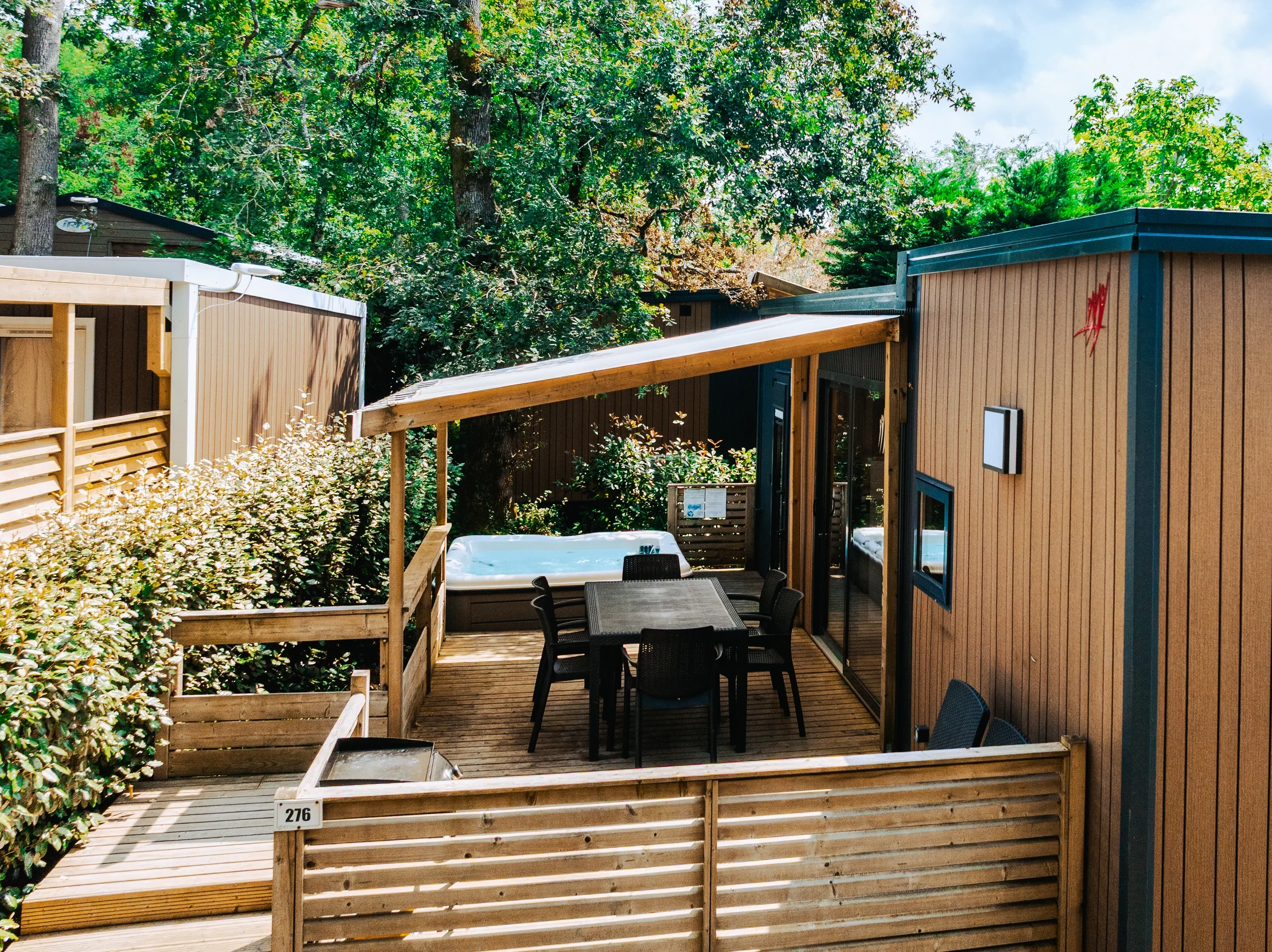 Terrasse en bois avec spa et table de repas au Camping le ruisseau, camping à Bidart.