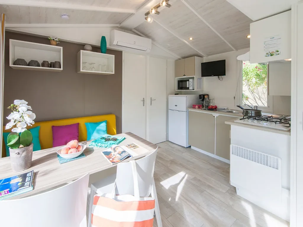 Cuisine ouverte et coin repas avec banquette jaune dans un hébergement insolite vers Biarritz au Camping le ruisseau.