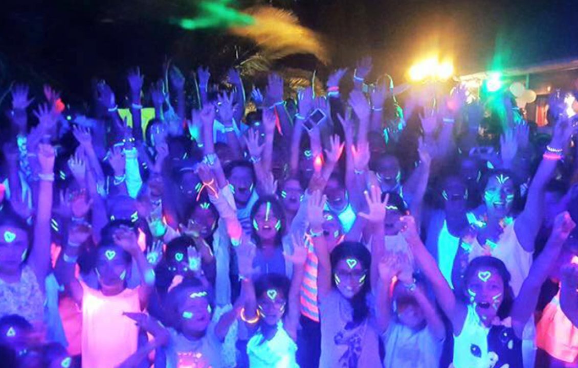 Participants les bras levés lors d’une soirée fluorescente au Camping le ruisseau.