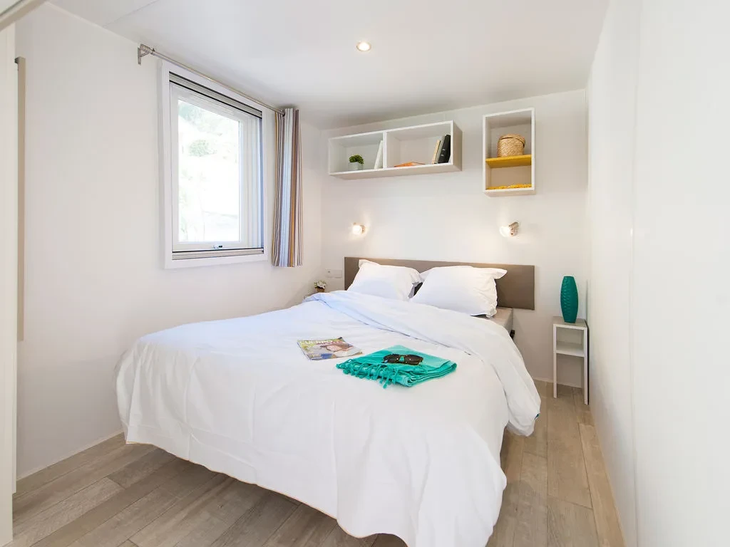 Chambre avec lit double et fenêtre dans un hébergement insolite vers Biarritz au Camping le ruisseau.