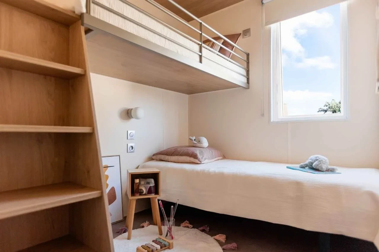 Chambre avec lits superposés et escalier de rangement en bois au Camping le ruisseau.