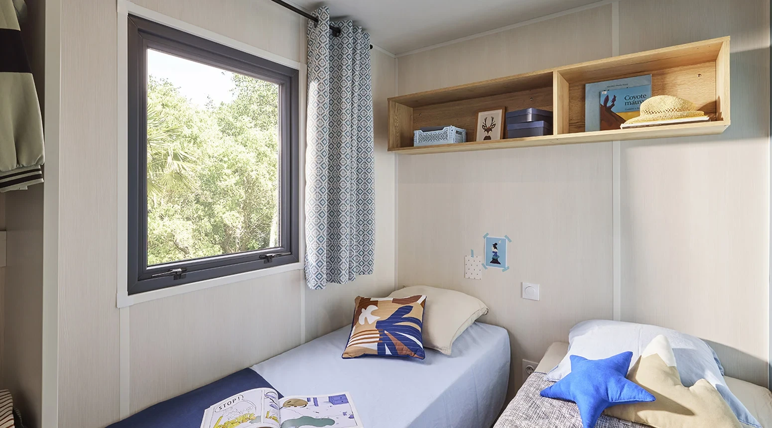 Chambre avec deux lits simples et coussins étoilés au Camping le ruisseau.