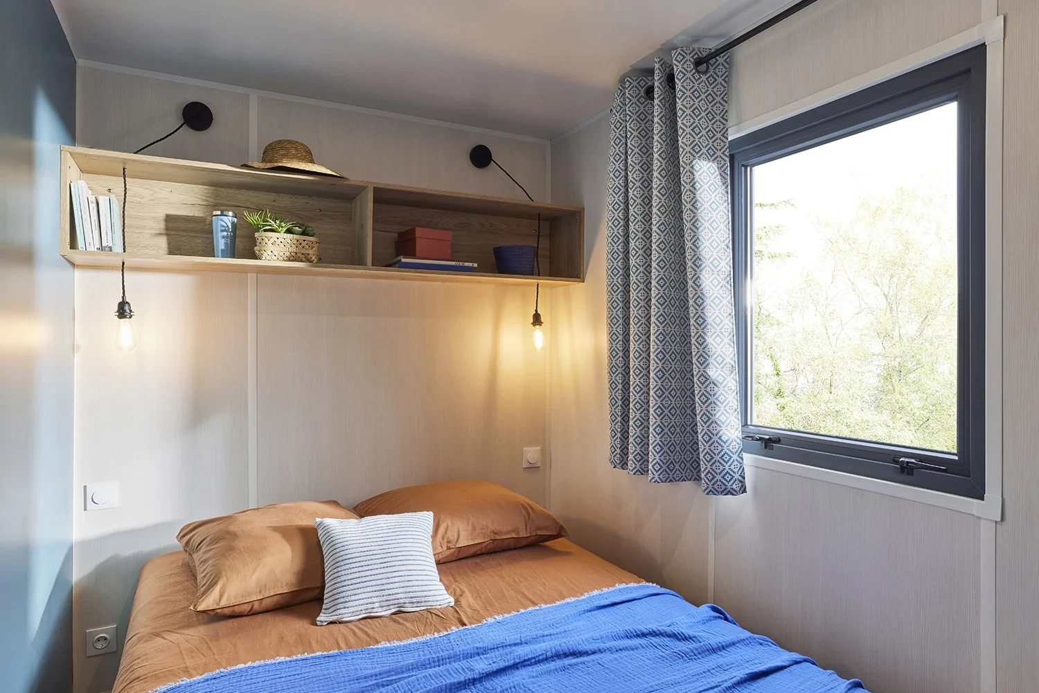 Chambre avec lit double d’un hébergement insolite vers Biarritz au Camping le ruisseau, avec deux lampes suspendues.
