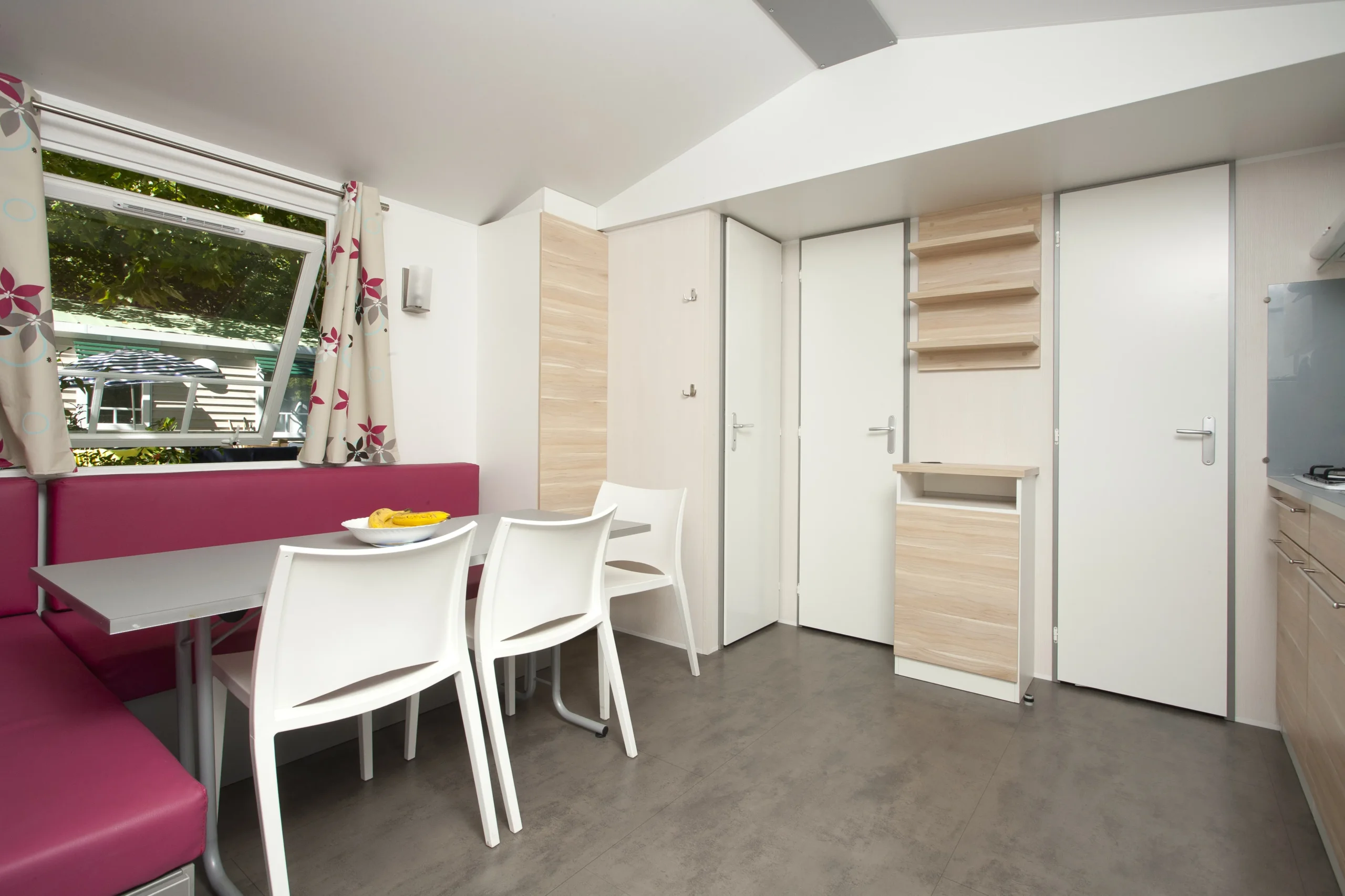 Coin repas avec banquette rose et chaises blanches dans un hébergement insolite vers Biarritz au Camping le ruisseau.