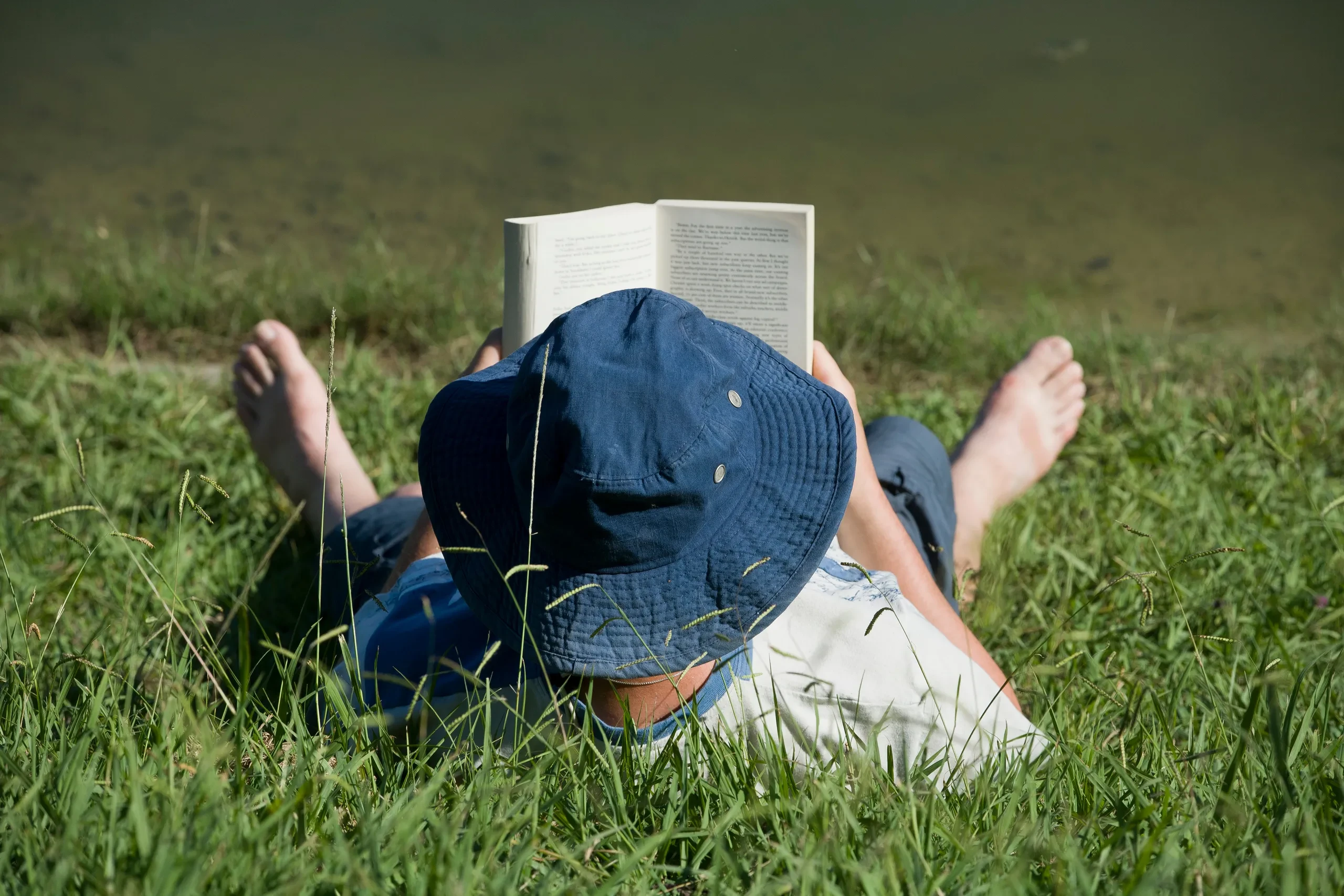 Vacancier allongé dans l’herbe lisant un livre au Camping le ruisseau, camping à Bidart.