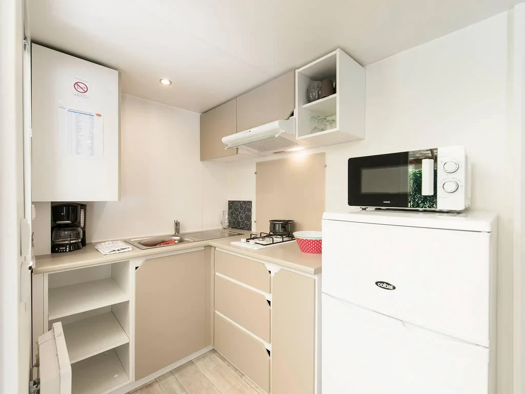 Cuisine en L avec plaques de cuisson, réfrigérateur et micro-ondes dans un hébergement insolite vers Biarritz du Camping le ruisseau.