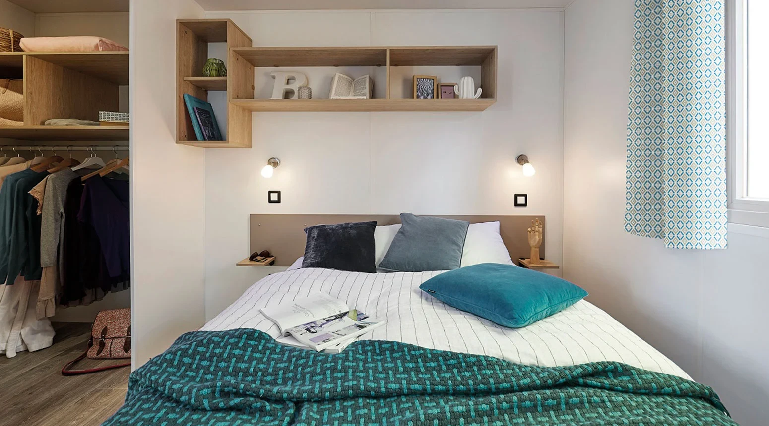Chambre du Camping le ruisseau avec lit double, liseuses et penderie ouverte.