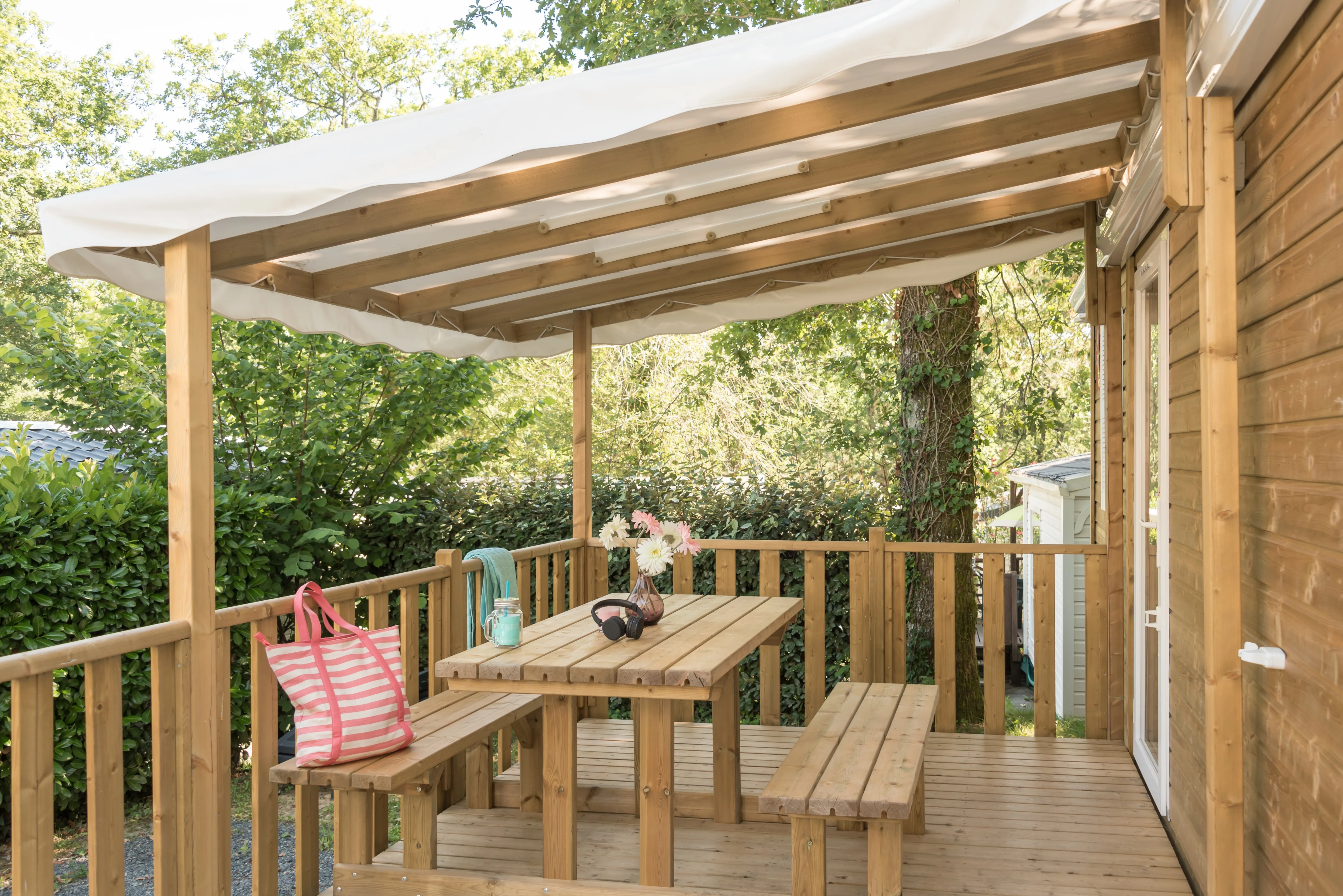 Terrasse en bois couverte avec table et bancs d’un bungalow en location à Biarritz au Camping le ruisseau.