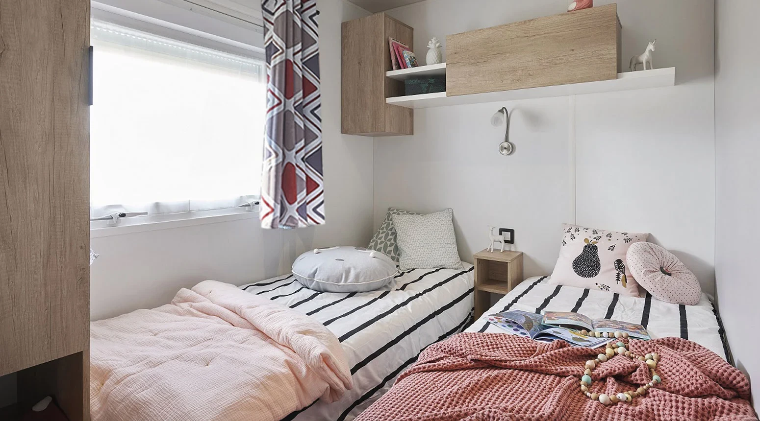 Chambre à deux lits simples d’un hébergement insolite vers Biarritz au Camping le ruisseau, avec rangements muraux en bois clair.
