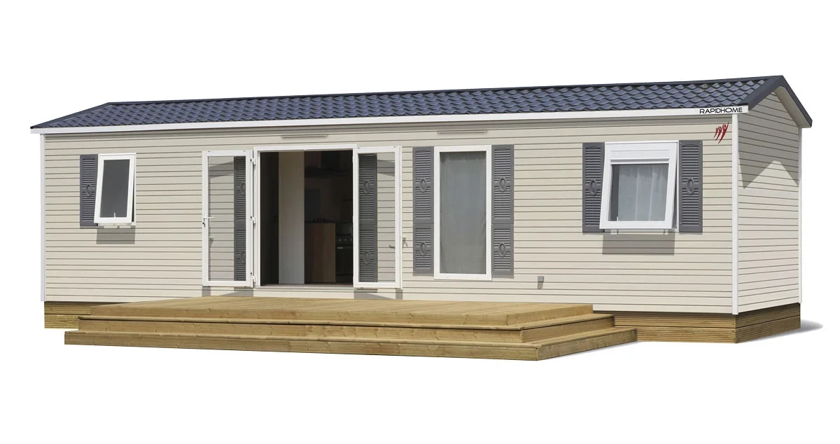 Mobil-home au bardage beige et aux volets gris, avec terrasse en bois et double porte vitrée ouverte.