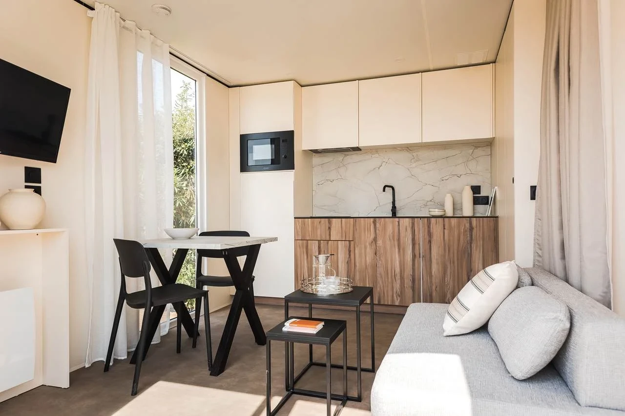 Cuisine ouverte sur le séjour avec coin repas et canapé dans un hébergement insolite vers Biarritz du Camping le ruisseau.
