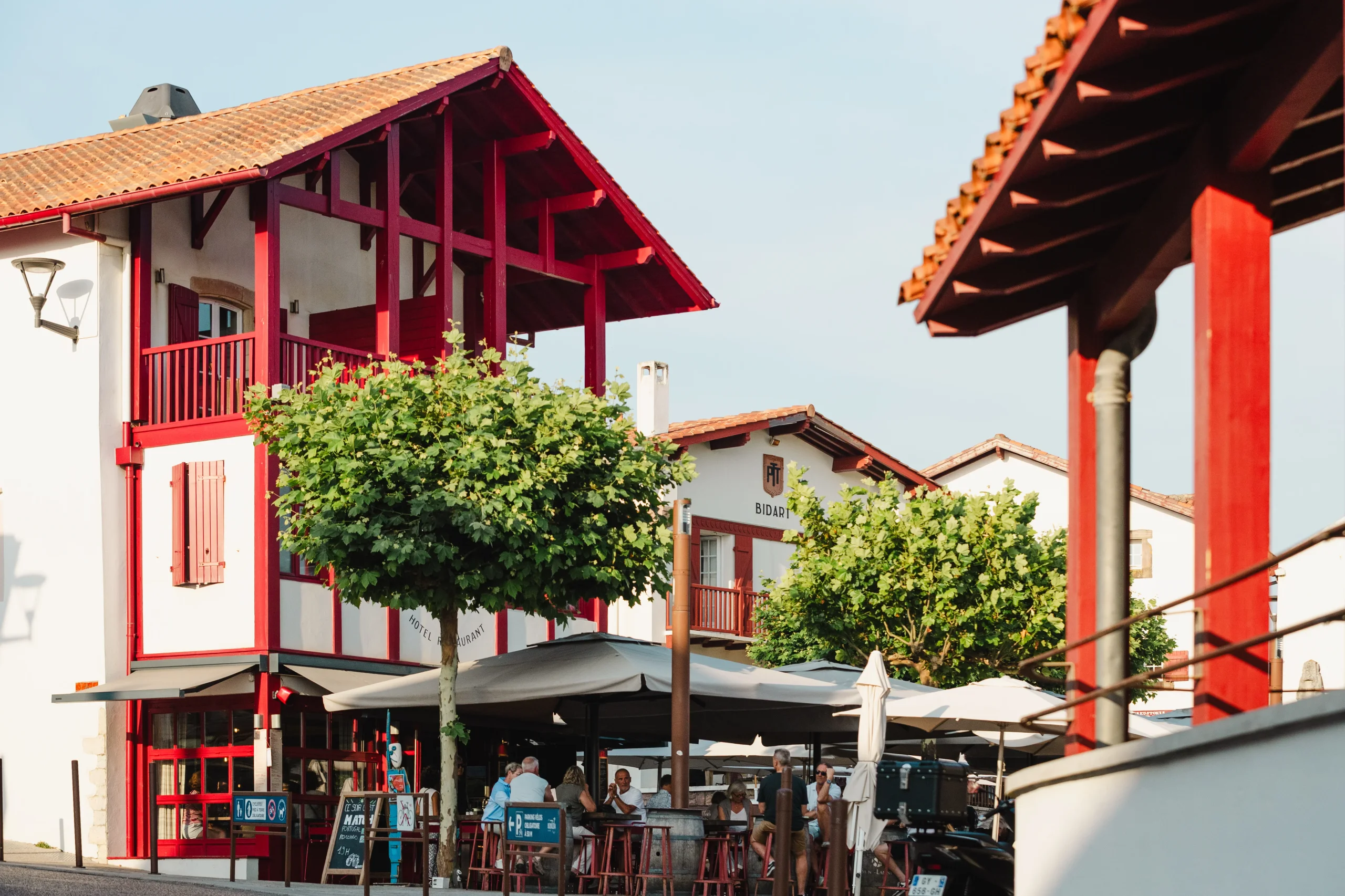 Maisons blanches à colombages rouges et terrasse de café dans le centre de Bidart.