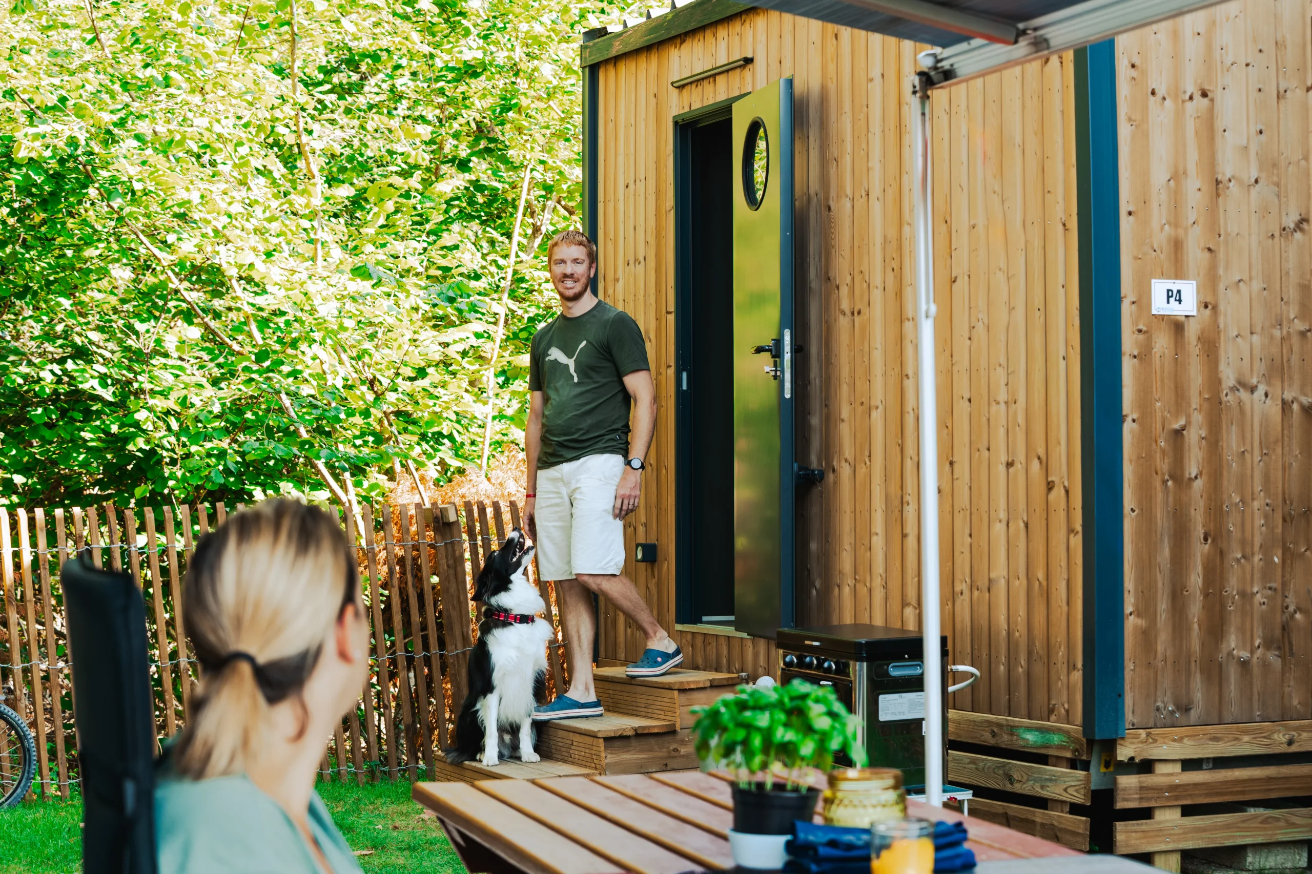 Un homme et son chien devant un hébergement insolite en bois du Camping le ruisseau, vers Biarritz.