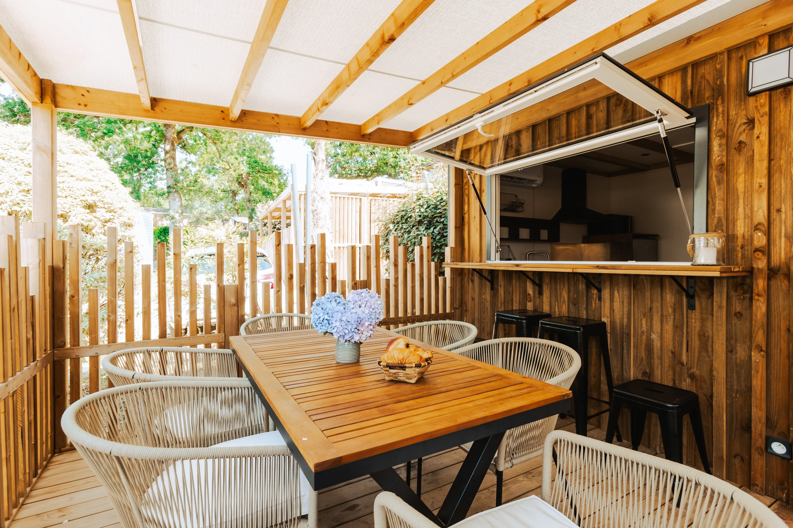 Terrasse avec table à manger et comptoir ouvert sur la cuisine au Camping le ruisseau, camping à Bidart.