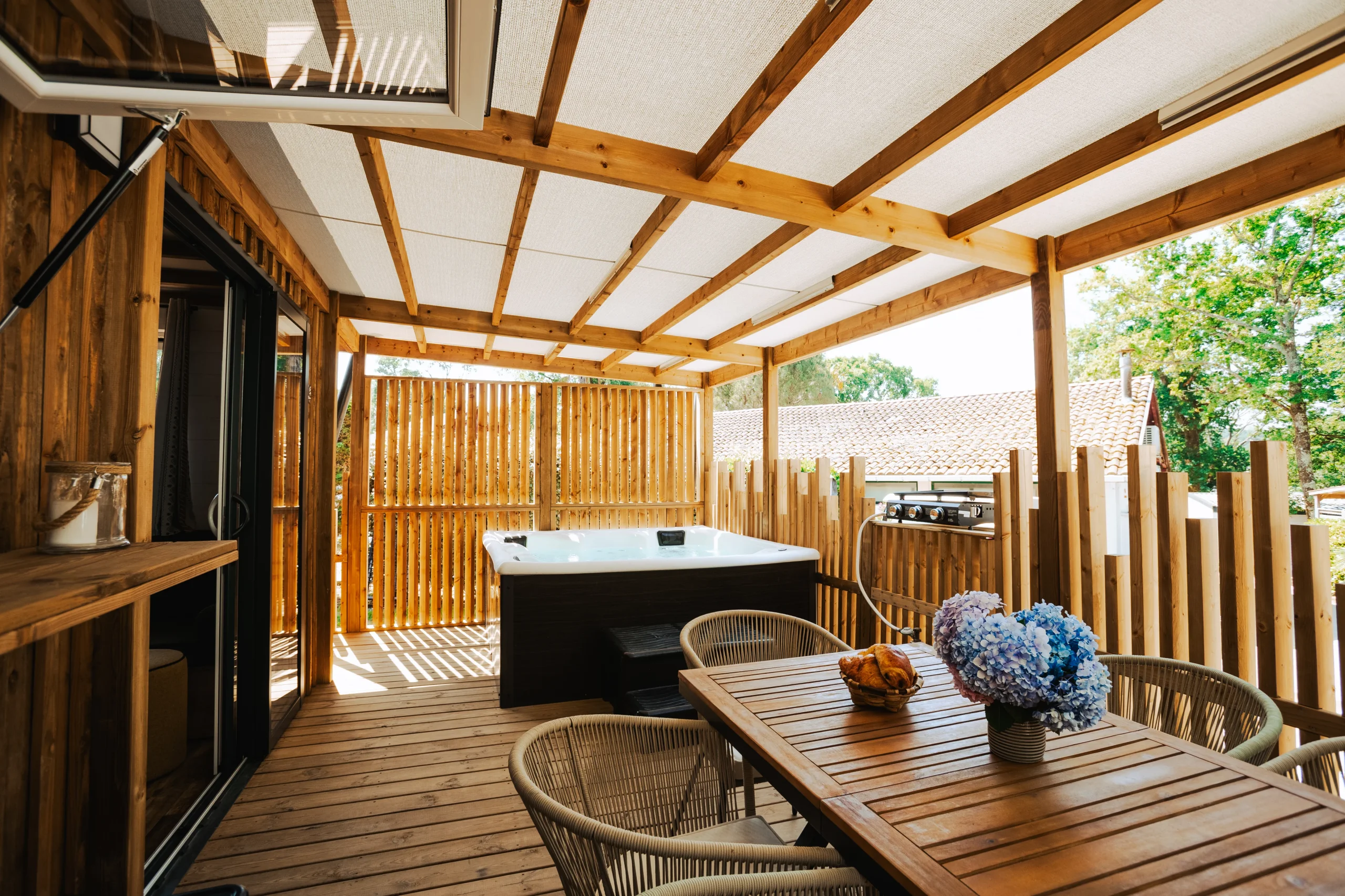 Spa et espace repas sur la terrasse couverte d’un hébergement insolite vers Biarritz au Camping le ruisseau.