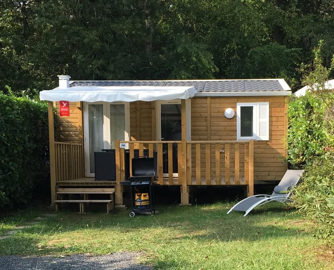 Hébergement insolite vers Biarritz au Camping le ruisseau, avec bardage en bois et terrasse couverte bordée de végétation.